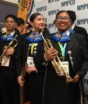 Students wearing mariachi attire holding trumpets